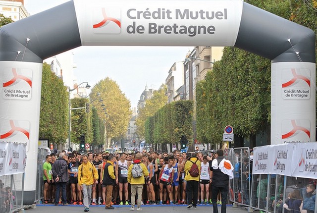 Une arche aux couleurs du Crédit Mutuel de Bretagne surplombe la foule de coureurs attendant le départ